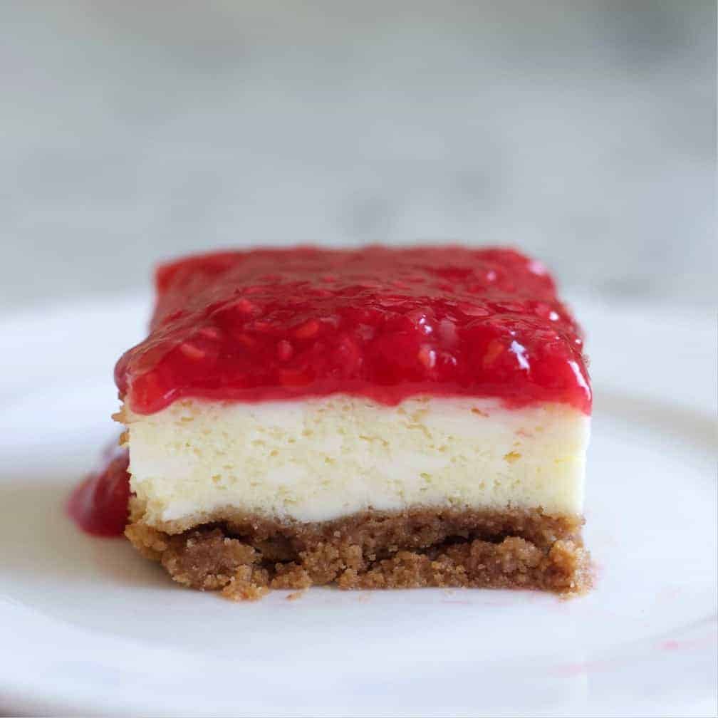 Raspberry Cheesecake square cut on a plate.