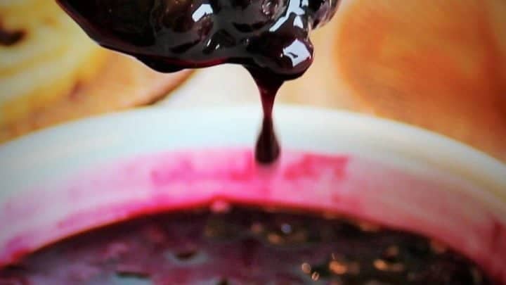 Blueberry sauce dripping off a spoon