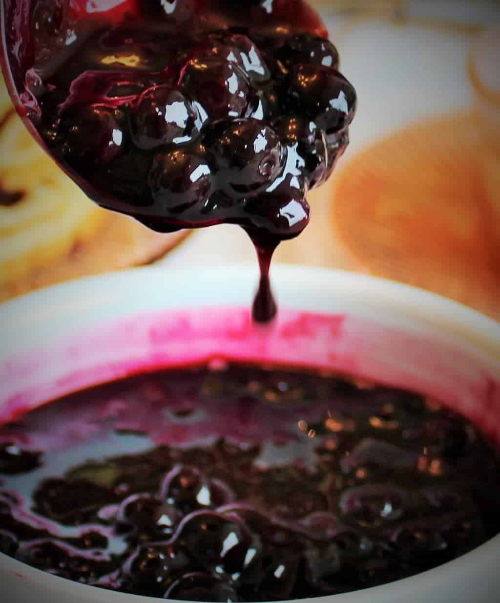 Blueberry sauce dripping off a spoon