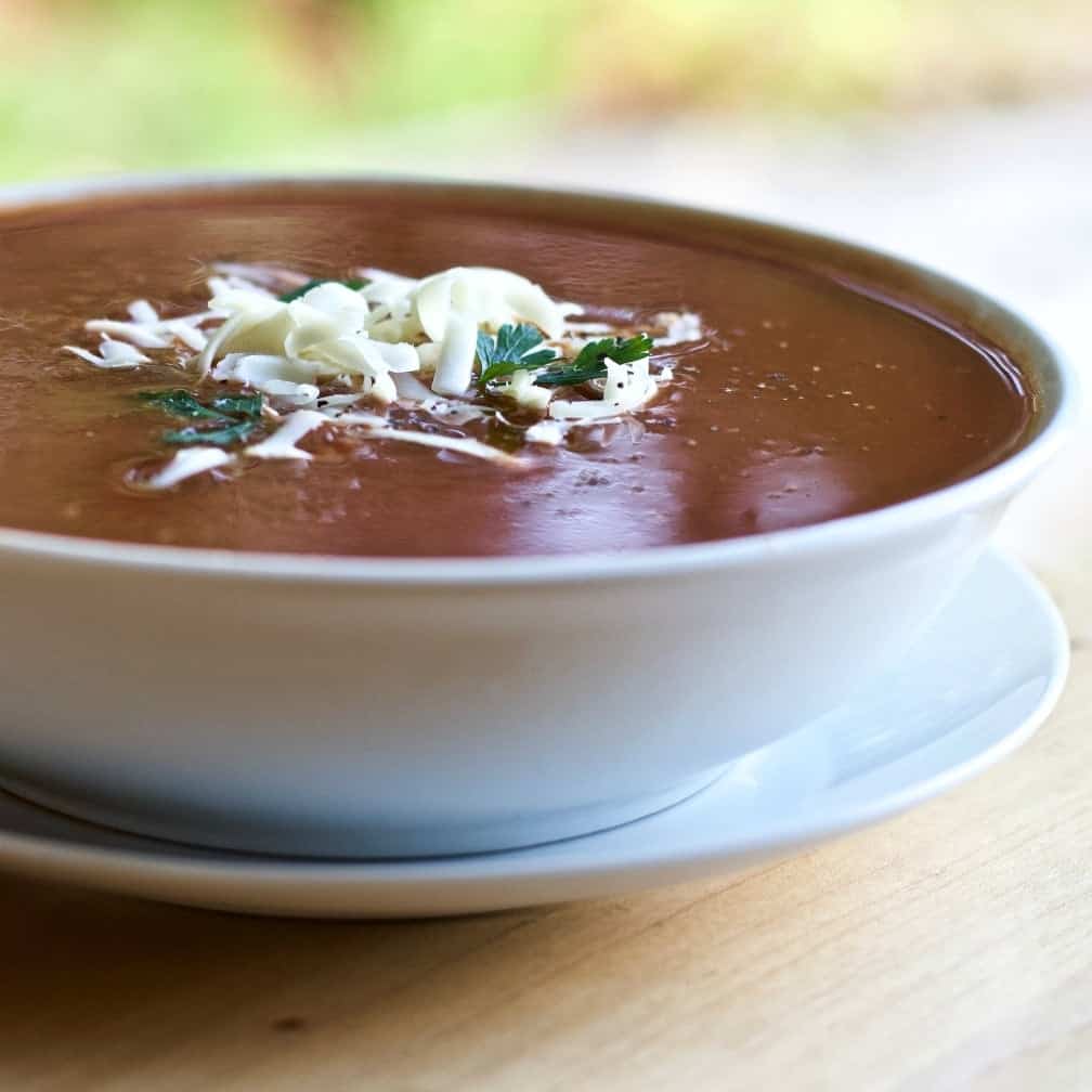 Roasted Pepper Tomato Soup in a white bowl with garnishes