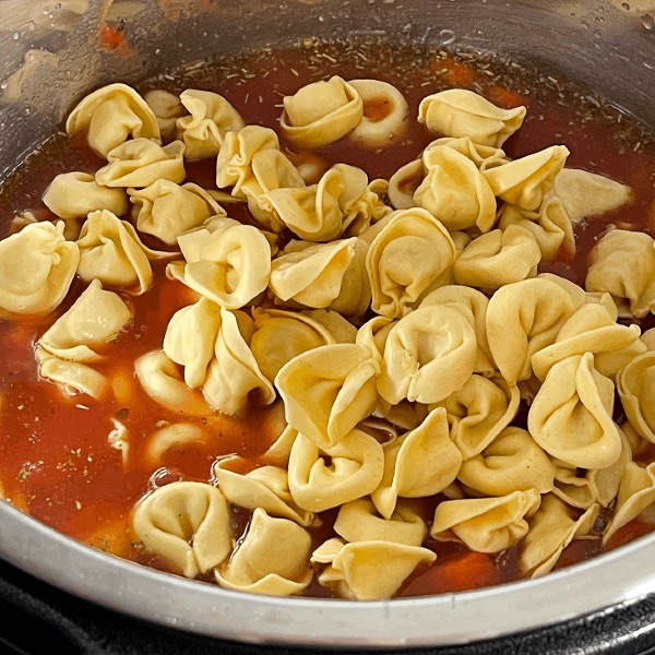 adding tortellini to tortellini sausage soup