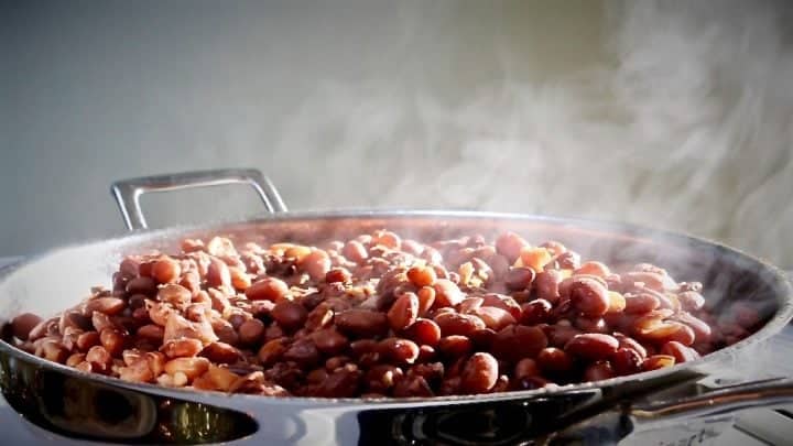 Making Homemade Refried Beans in a skillet. Refrying cooked pinto beans is a VERY frugal way to add delicious flavor to your Mexican meals. Add your own touches and use your Instant Pot to make this whole process a snap! Read more on Homemade Food Junkie! #refriedbeansrecipes #beanrecipes #mexicancooking #mexicancuisine #mexicanrecipes
