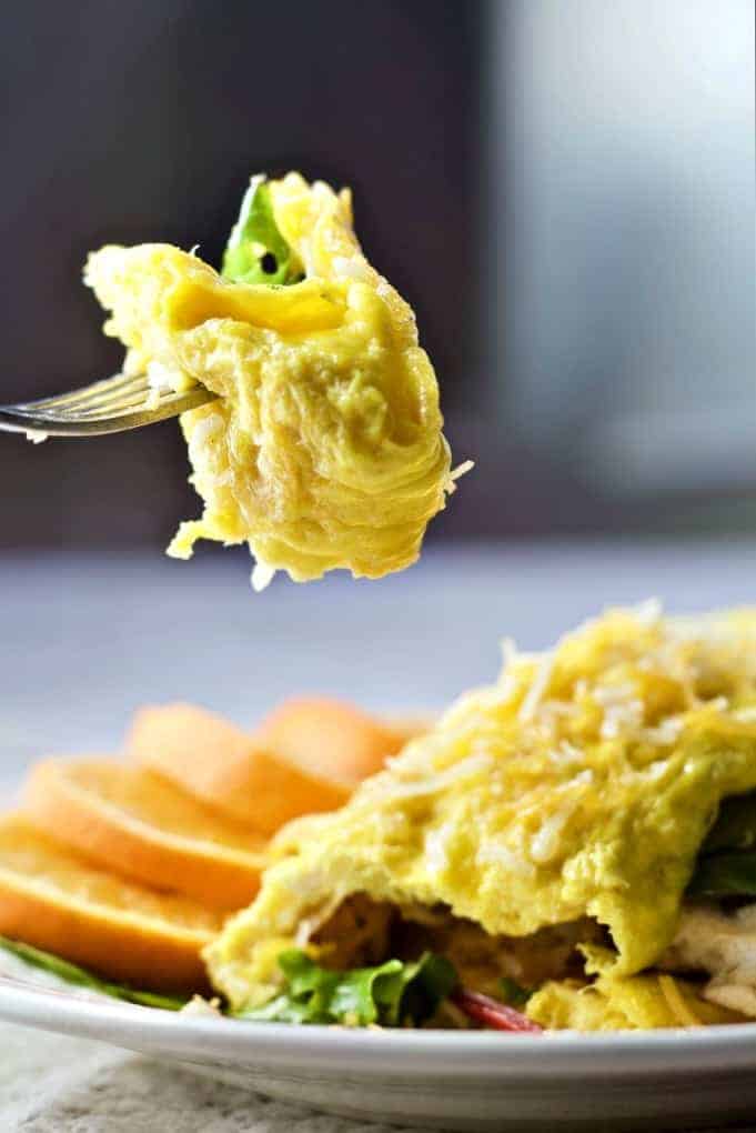 Omelette on a plate with a fork full of omelette above