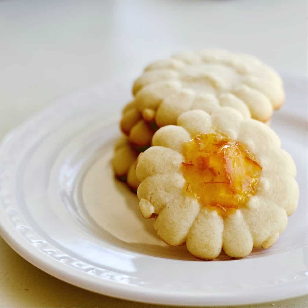 Spritz cookie recipe on a plate with marmalade in the center.