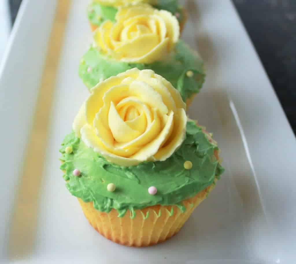 Delicious Lemon Cupcakes with a green frosting and bright yellow rose on top. 