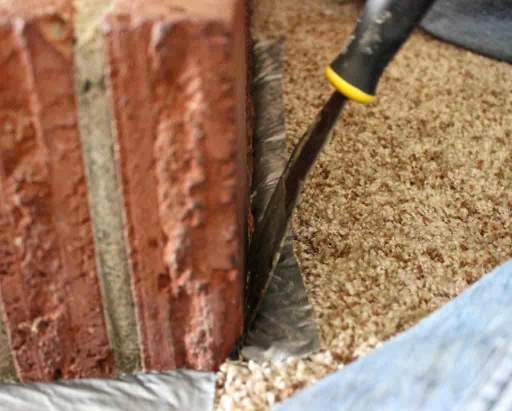Fireplace Overhaul-Use a paint scraper to push down the carpet when masking off