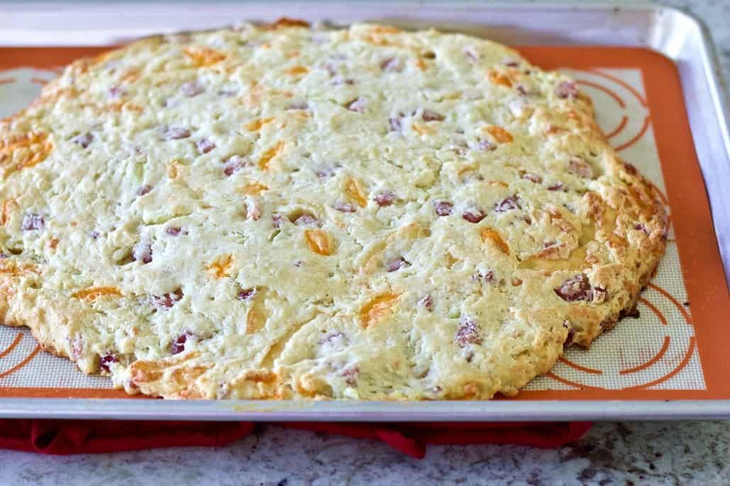 Ham and Cheese Scones Recipe 8 ham and cheese scones in a circle on an oiled baking sheet.