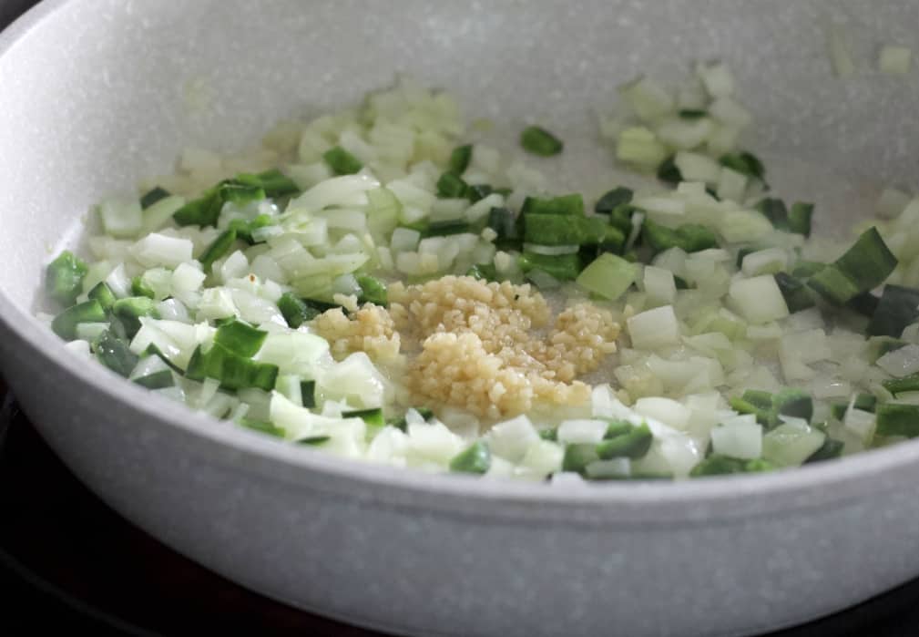 frying onions, pepper and garlic in a white skillet-corn chowder