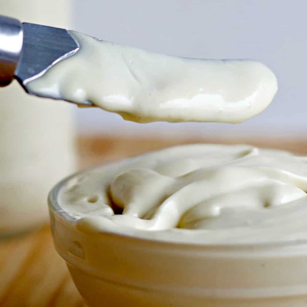 Healthy Homemade mayonnaise recipe. Mayonnaise in a small clear bowl scooped with a knife