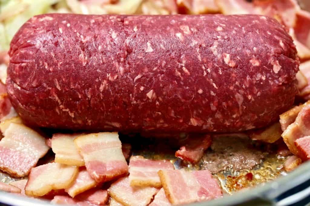 Browning ground moose meat and bacon in a skillet