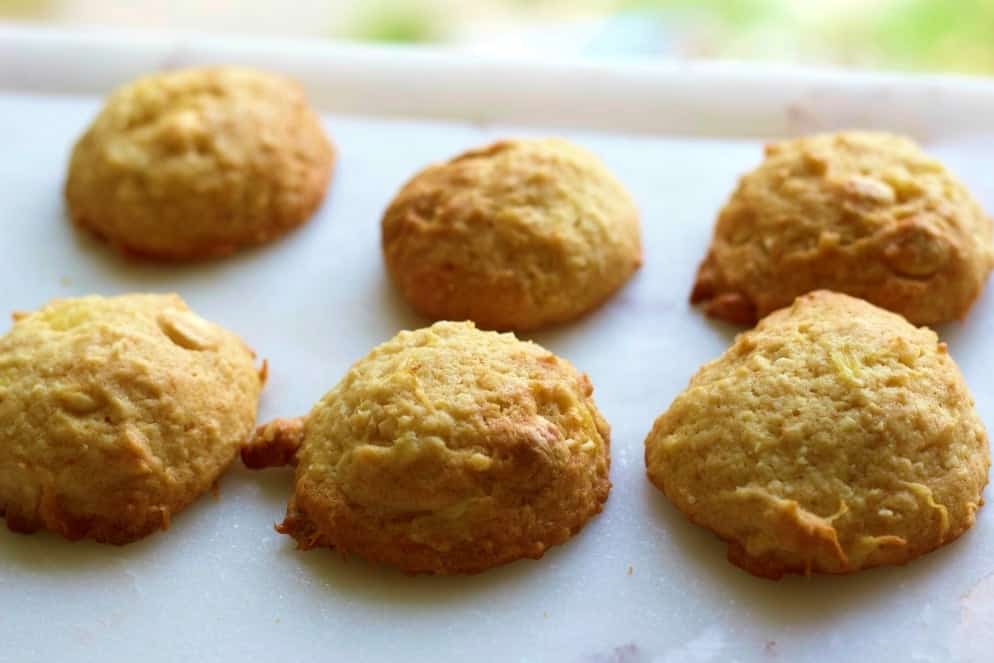 Pineapple White Chocolate Macadamia Cookies on a white marble plate. Unfrosted.