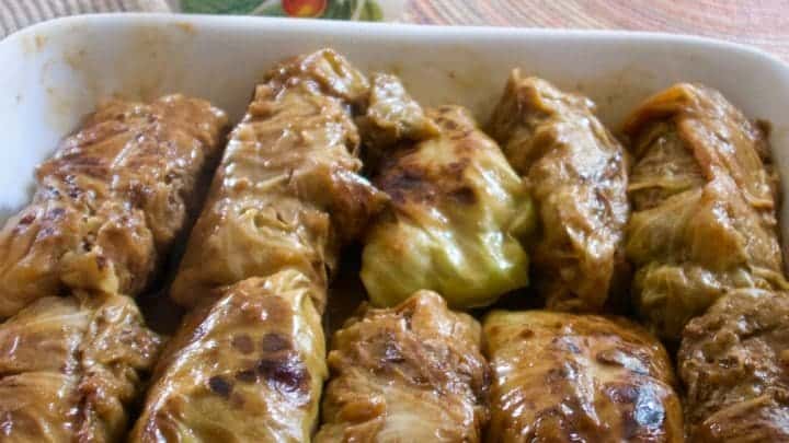 Cabbage rolls in a serving dish with gravy in a gravy server
