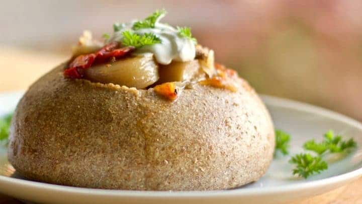 Honey Oat Bread Bowl with Hamburger soup on a white plate with parsley