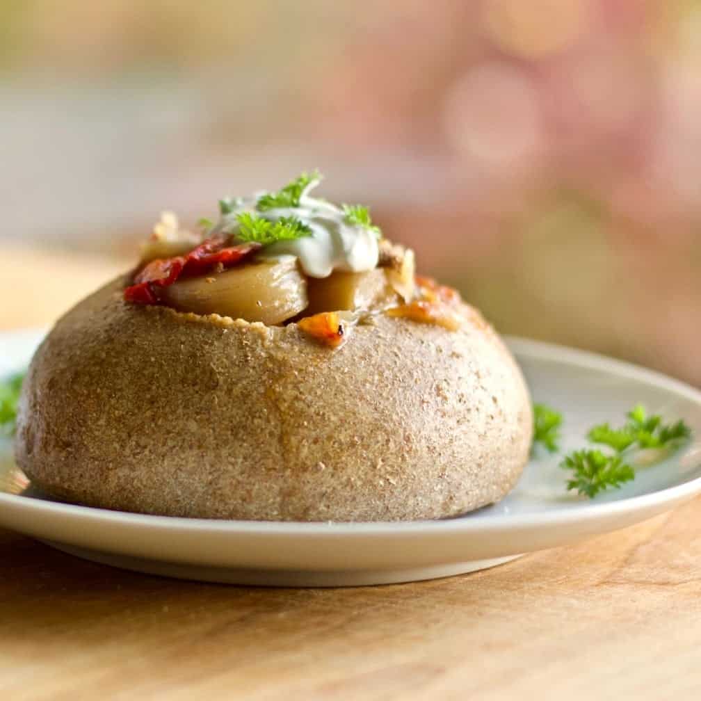 Honey Oat Bread Bowl with Hamburger soup on a white plate with parsley