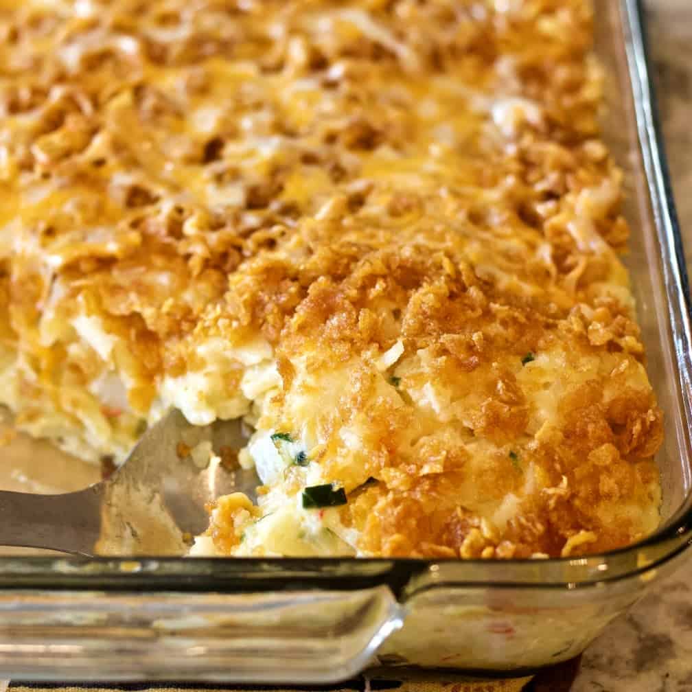 Funeral Potatoes with one scoop removed to reveal the creamy interior.