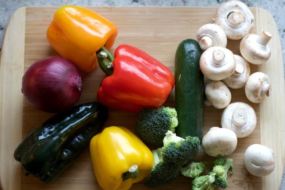 Fresh vegetables for roasting on a sheet pan. red onion, Sweet red pepper, roasting pepper, zucchini, broccoli and white mushrooms.