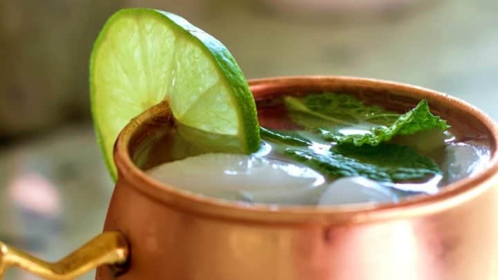 Moscow mule vodka drink in a copper mug with lime and mint leaves.