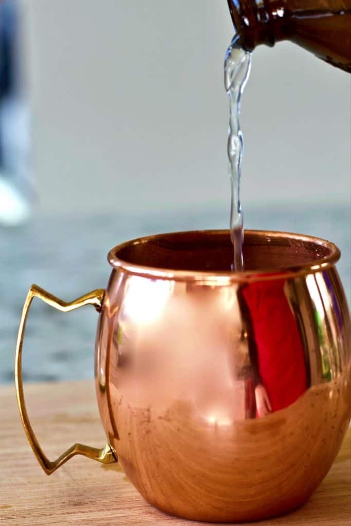 pouring vodka into a copper mug