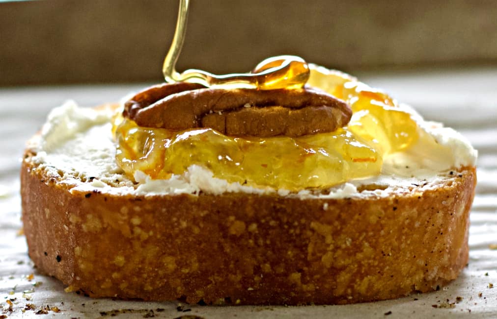 Goat Cheese Crostini Appetizer with Marmalade and Pecan 8 drizzling honey on the crostini.