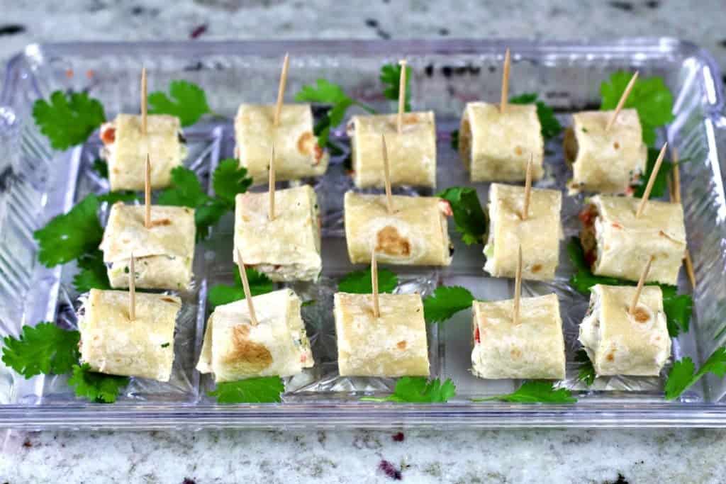 Cream cheese tortilla pinwheels on a garnished party tray.