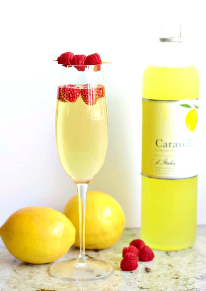 Limoncello Prosecco in a champagne flute garnished with raspberries.