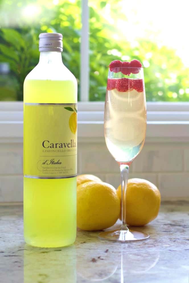 Limoncello Prosecco Cocktail with lemons and a bottle of Caravella Limoncello