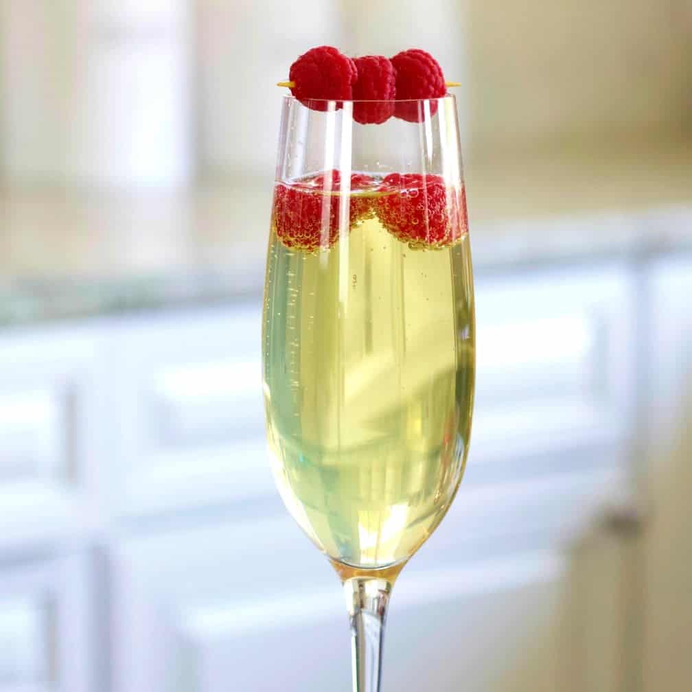 Limoncello prosecco in a champagne flute garnished with raspberries.