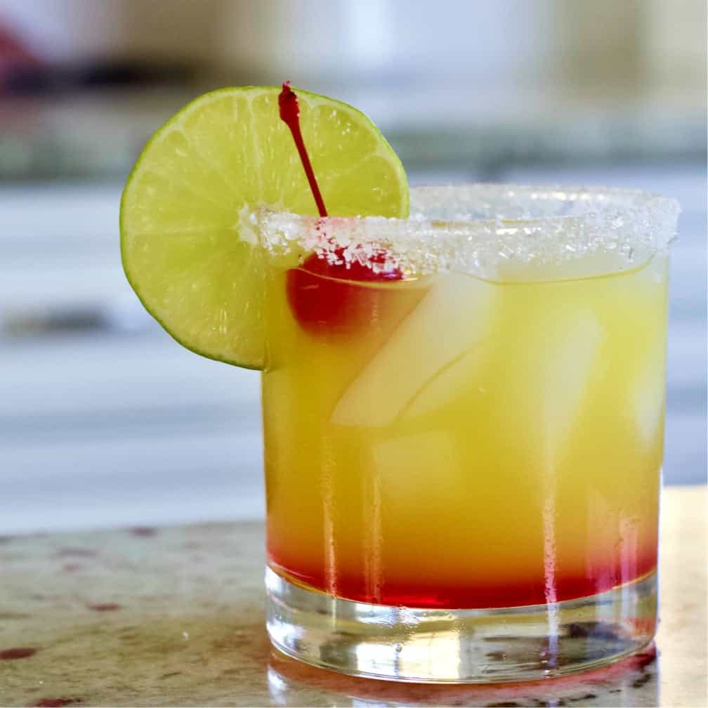 Tequila Sunrise Cocktail garnished with a lime wheel and cherry