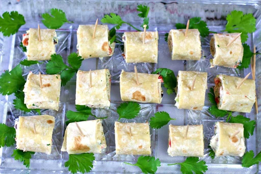 Tortilla pinwheels on a party tray with fresh cilantro
