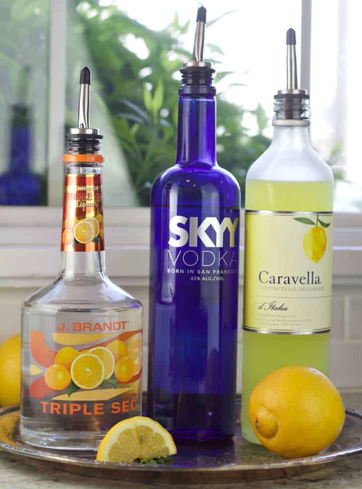 triple sec, skyy vodka and limoncello on a tray with lemons