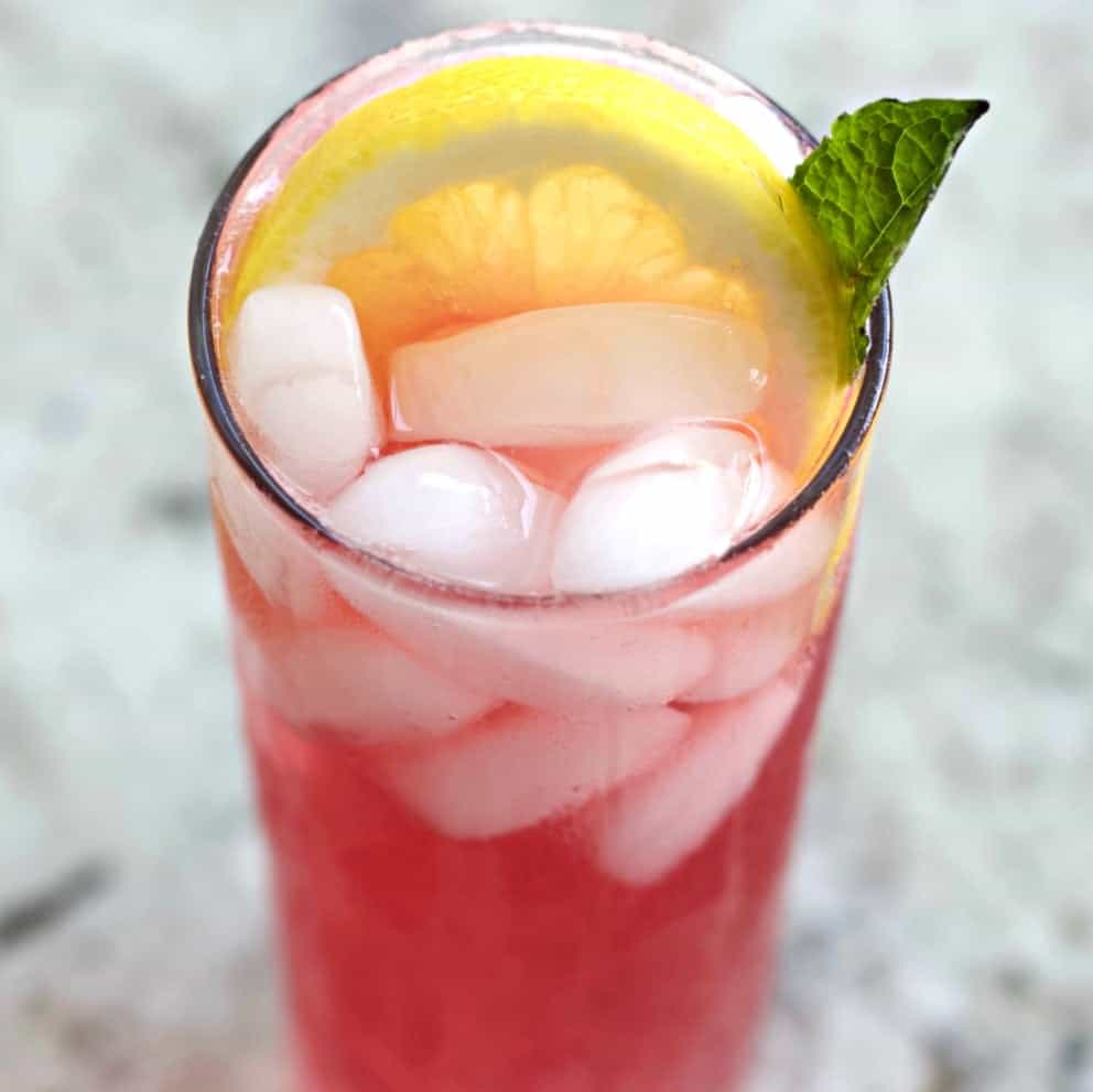 pink lemonade cocktail garnished with a lime wheel and mint leaf.