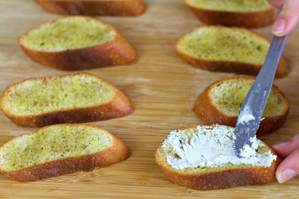 spreading goat cheese on bruschetta