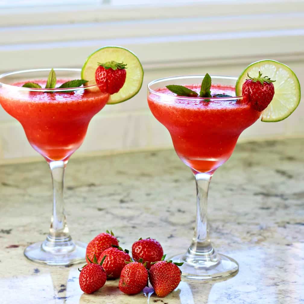 Strawberry Daiquiri Recipe with Malibu Coconut Rum 1 Frozen strawberry daiquiris with whole fresh strawberries on the counter around them.
