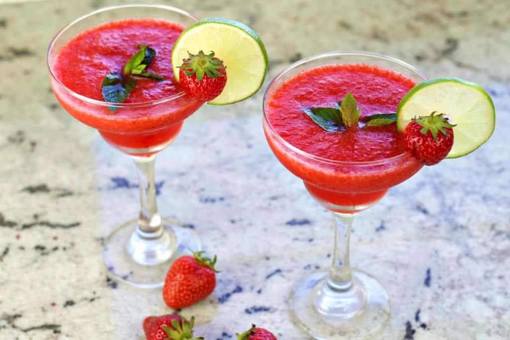 Strawberry Daiquiri Recipe with Malibu Coconut Rum 3 Two strawberry daiquiris garnished with mint leaves, lime wheels and a whole fresh strawberry.