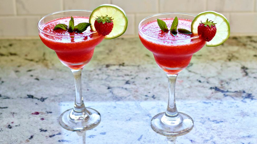 Strawberry Daiquiri Recipe with Malibu Coconut Rum 2 Frozen Strawberry Daiquiris sitting on a counter fully garnished.