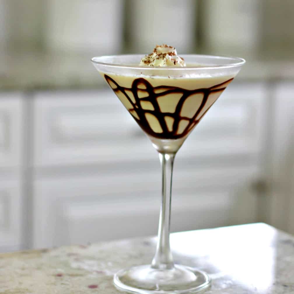 martini glass with chocolate sauce lines in the glass and whipped cream on top with shaved chocolate.