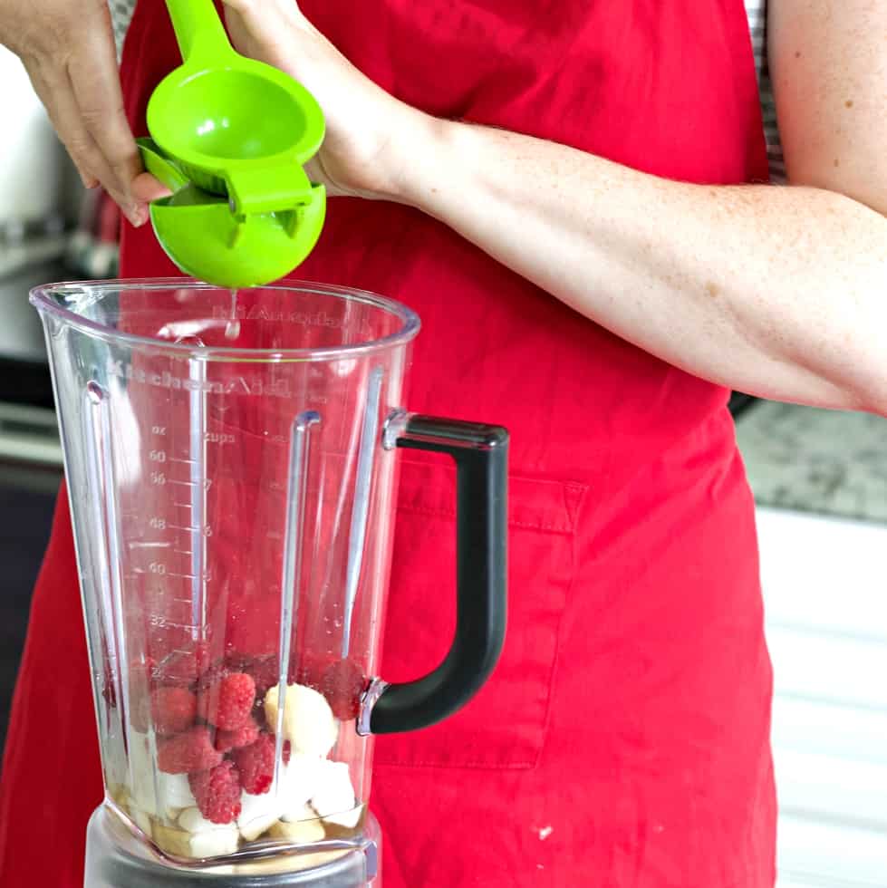 squeezing a lime into a fruit filled blender