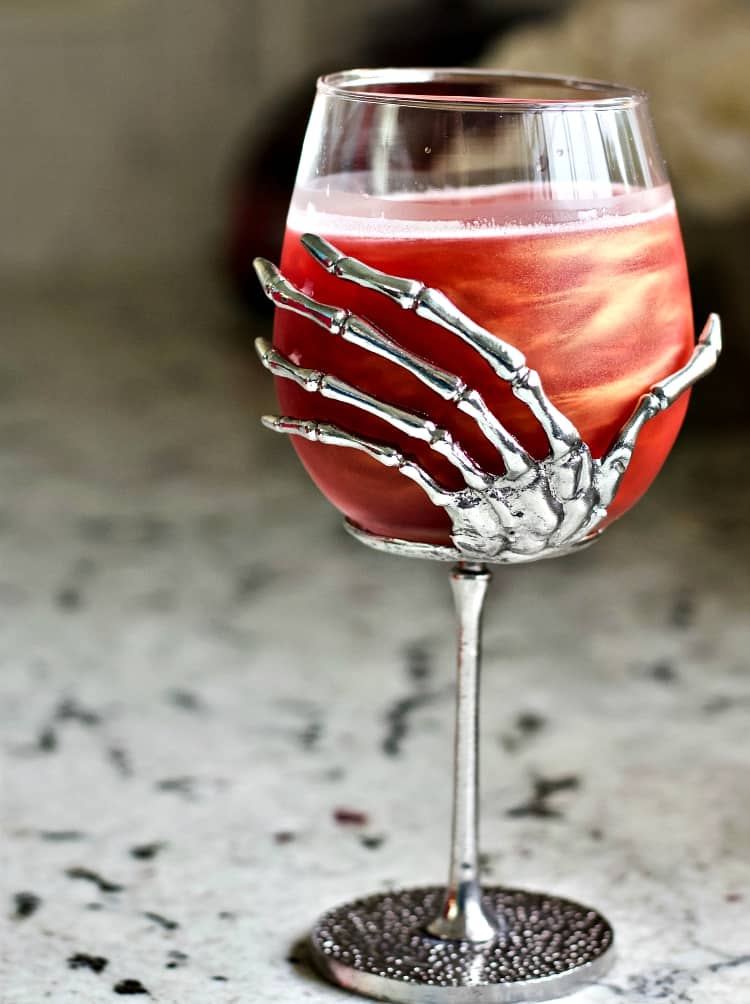 Swirling Poison Apple in a skeleton hand glass.
