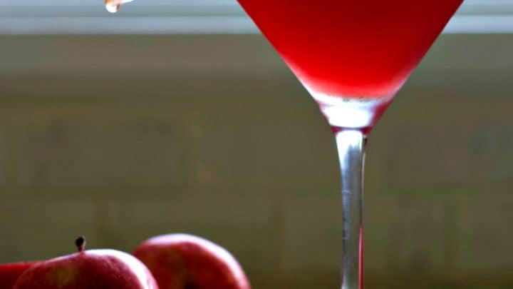 Garnished Washington Apple Drink with apples on a wooden board.