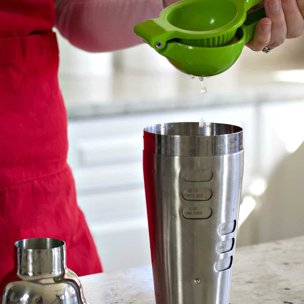 squeezing a lemon into a cocktail shaker
