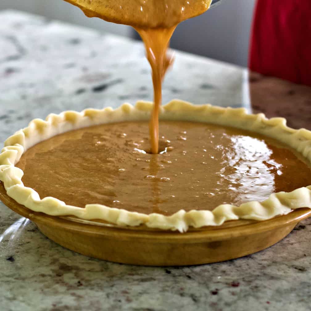 sweet potato pumpkin pie-pouring batter in pie shell