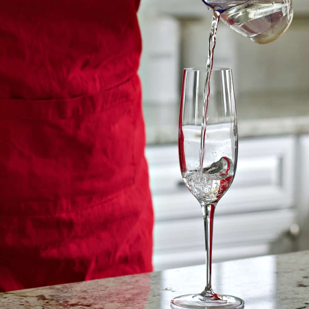 White Cranberry Mimosa Recipe with Rosemary 13 Pouring white cranberry juice into a champagne flute