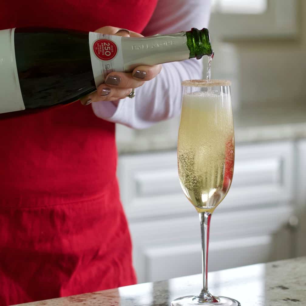 pouring sparkling wine into rimmed glass