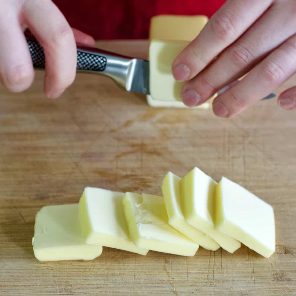 cutting butter into chunks on a wooden board