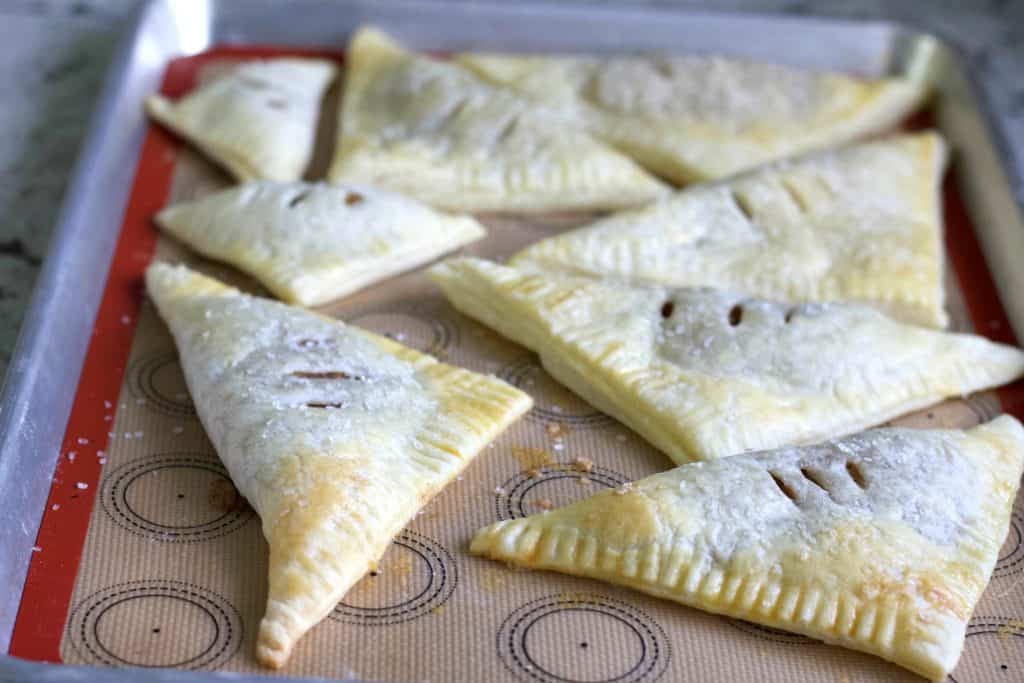 Homemade Apple Turnover Recipe with Puff Pastry 5 Freshly baked Apple Turnovers on a baking sheet.