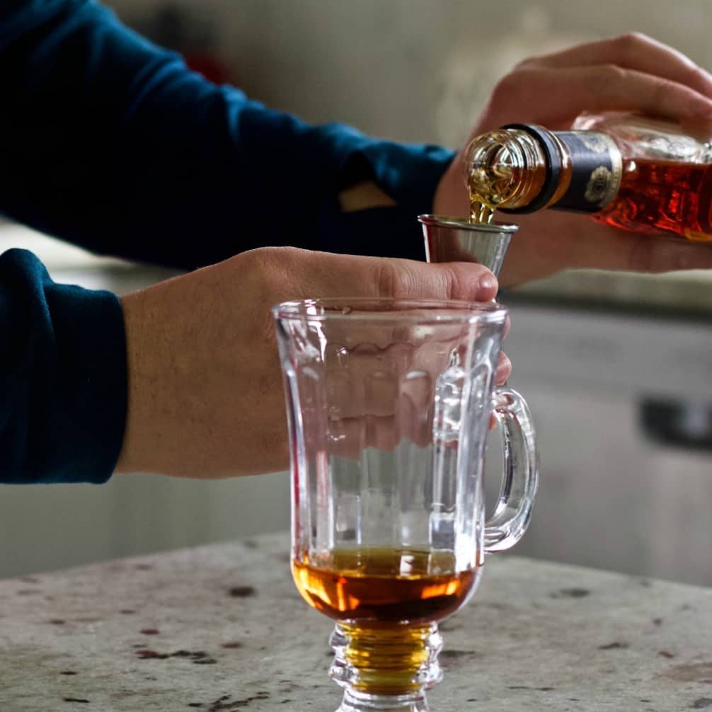 pouring brandy into a hot mug.