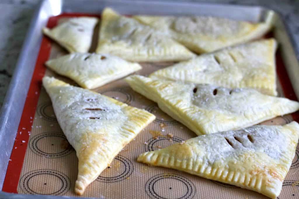 Homemade Apple Turnover Recipe with Puff Pastry 21 baked apple turnovers on baking sheet.