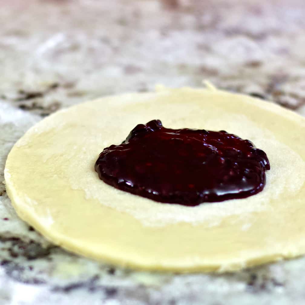 dough circle with egg washed edge and filling.-hand pies