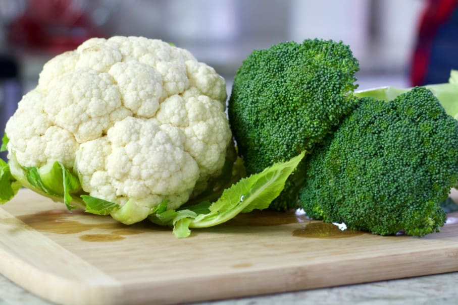 fresh cauliflower and broccoli on a cutting board.