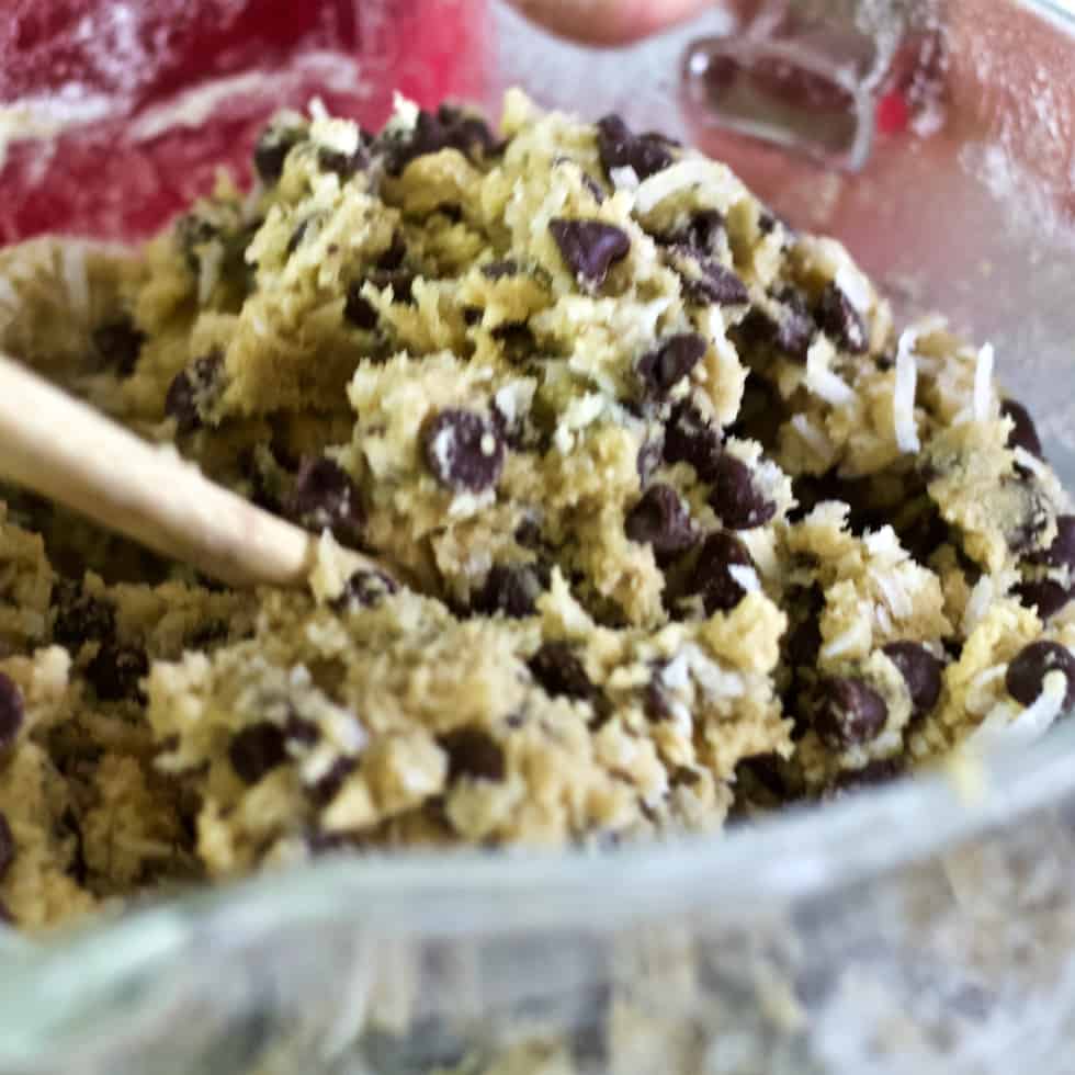 stirring chocolate chips into almond joy cookie dough